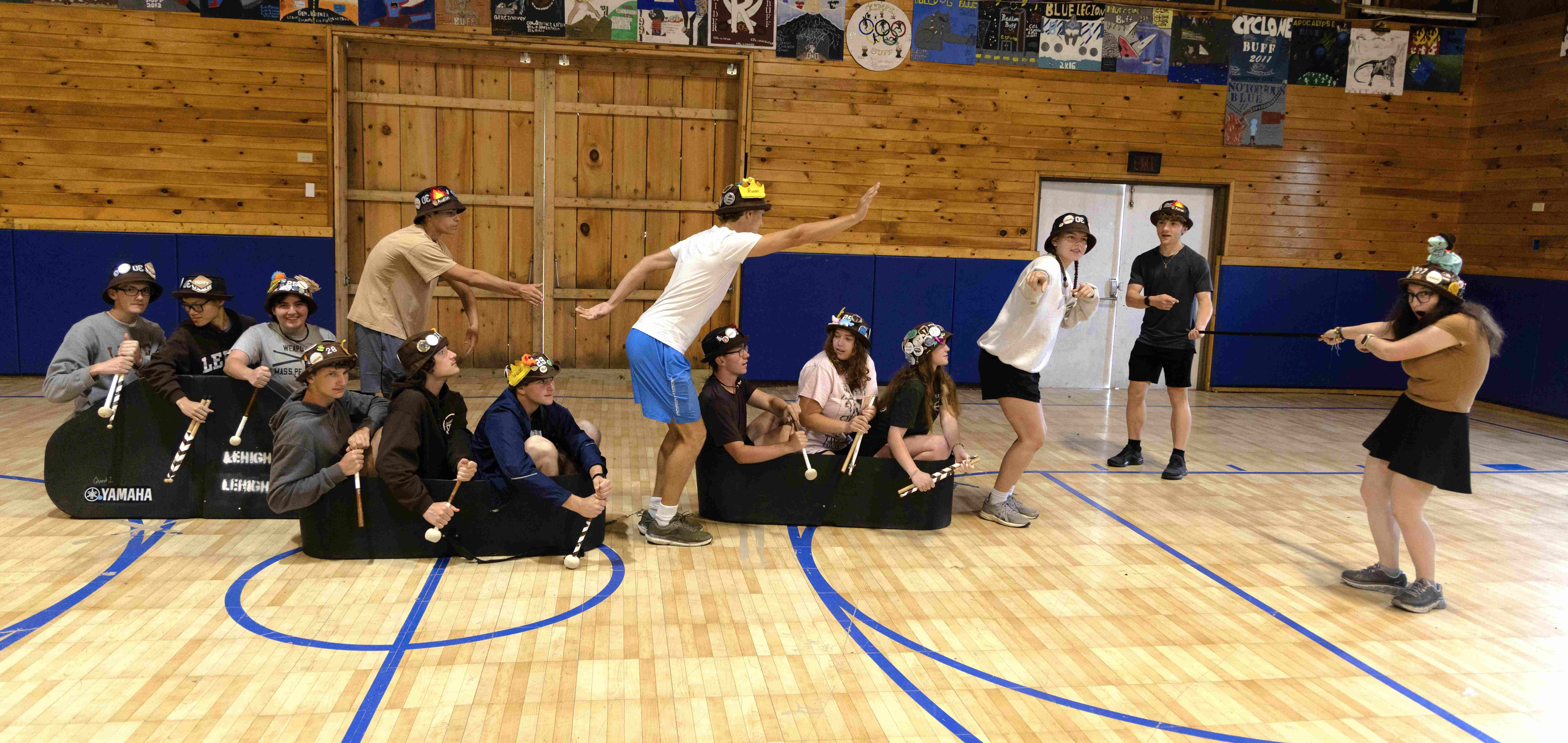 Ranks 3 and 12 pretending to race boats, with one person dancing at the front of each of the three boats.